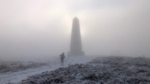 A mist covered Easby Moor, with a lone runner approcahing the silhouetted Capt. Cook's Monument 