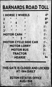 A black-and-white toll board, fixed to the wall of Toll Cottage on Barnard's Road near Egton Bridge. Issued by "EGTON ESTATES OFFICE" in August 1948, it lists charges for every conceivable form of transport — horse-drawn, motorised, and agricultural. A hearse paid sixpence. A motor bus paid three shillings. The gate closed at ten o'clock every night.
